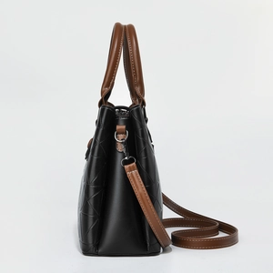 Detail view of black and brown leather handbag with geometric embossed patterns and silver hooks