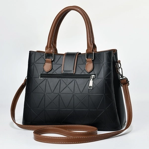 Macro detail of black geometric embossed leather tote bag with brown straps and white stitching