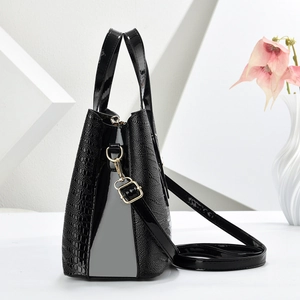 Detail of glossy patent and crocodile embossed leather texture on black handbag