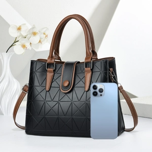 Detail of embossed geometric tote bag next to a smartphone for size comparison