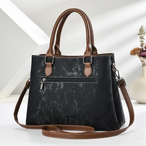 Close-up of vintage black textured handbag with brown leather straps and silver zipper
