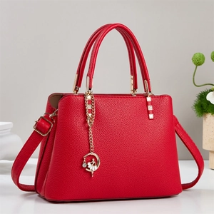 Detail of red pebbled leather handbag with golden hardware and ballerina charm