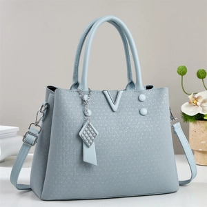 Close-up of light blue handbag with V-shaped metal logo and textured woven finish
