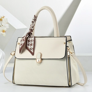 Détail du sac crème avec fermoir rotatif doré et foulard en soie pied-de-poule noué