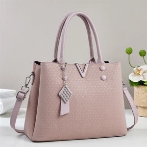 Detail of dusty rose woven leather handbag with silver V metal logo and charm
