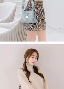 Detail view of light blue shoulder bag with V-shaped texture and gold bow charm detail