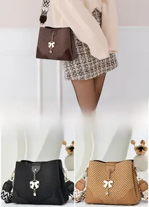 Detail of herringbone bucket bag featuring rhinestone bow charm and geometric strap