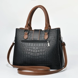 Detail of crocodile pattern texture and silver hardware on black and brown tote bag