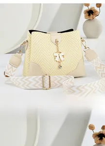 Close-up of woven bucket bag featuring herringbone pattern and rhinestone bow charm