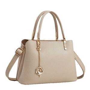 Elegant beige pebbled leather tote bag with gold floral pendant and adjustable strap