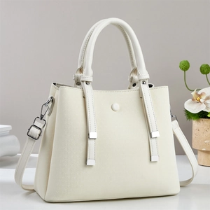 Close-up of cream crossbody bag with woven texture, dual handles and silver hardware
