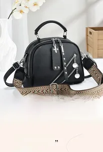 Détail du sac à main noir en cuir grainé avec bandoulière tissée et finitions argentées