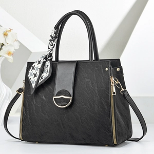 Elegant black leather tote bag with gold hardware and silk scarf on a white background