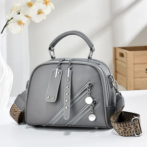 Sac bandoulière gris avec rivets et sangle tissée géométrique dans un cadre moderne