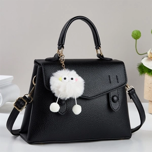 Black lychee texture handbag with plush monster pendant and adjustable shoulder strap