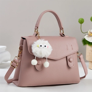 Close-up of pink litchi grain leather handbag featuring asymmetrical flap and plush charm