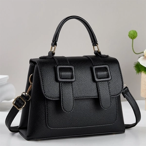 Minimalist black lychee leather handbag with golden hardware and adjustable crossbody strap