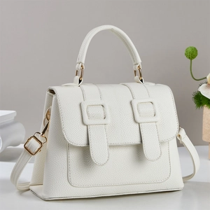 Close-up of white lychee textured crossbody bag with gold hardware and elegant handles