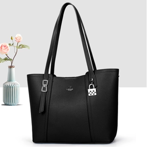 Detailed view of black lychee grain leather tote bag with silver metal brand logo and charm