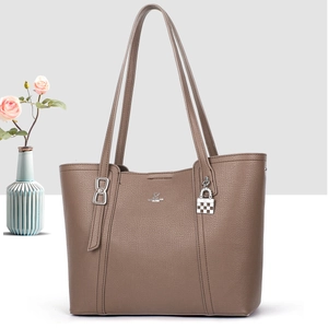 Close-up of taupe litchi grain faux leather tote bag with silver logo and pendant