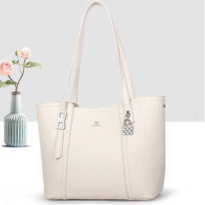 Detail of creamy white tote bag featuring lychee grain texture and metal checkerboard pendant
