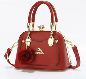 Detailed view of red shell-shaped handbag with 3D rose charm and crystal clasp closure