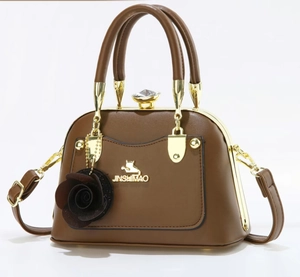 Detailed view of brown leather handbag with gold cat logo and rose flower charm accessory