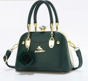 Detail of dark green leather handbag featuring golden cat logo and rose pendant