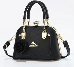 Detail of black leather handbag with gold cat logo and crystal clasp on white background