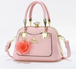 Pink crossbody handbag detail with golden cat logo and large rose charm pendant