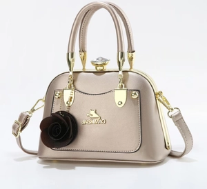 Detail of champagne gold metallic shell bag with rose charm and crystal clasp closure
