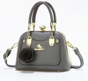 Detail of dark gray handbag featuring golden cat logo and 3D rose ornament accents