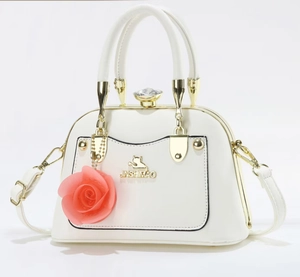 Detail of white shell handbag with gold cat logo and pink silk rose charm