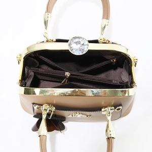 Interior view of brown handbag showing three compartments and gold hardware closure