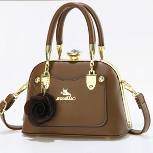 Elegant brown leather tote bag with vintage metal clasp and floral charm accessory