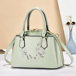 Nahaufnahme der minzgrünen Muscheltasche mit floraler Bestickung und goldener Hardware