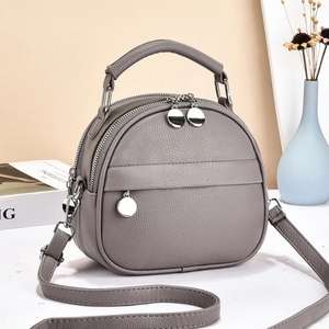 Close-up of grey litchi texture leather handbag with silver charm and double zipper