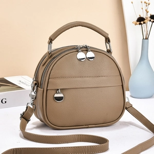 Detail of coffee brown lychee pattern leather handbag with silver double zipper closures
