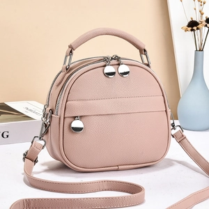 Close-up of small light pink crossbody bag with pebbled leather texture and silver hardware