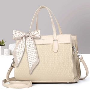Beige patchwork handbag with scarf bow and detachable strap in a minimalist setting