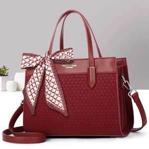 Elegant burgundy tote bag with woven texture, decorative scarf, and adjustable shoulder strap