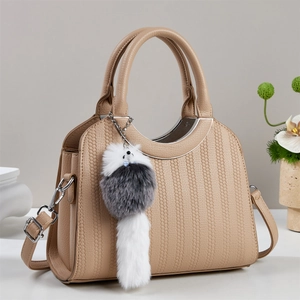Dettaglio della borsa a secchiello in ecopelle beige con texture a grana e ciondolo a coda di volpe