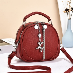 Red textured leather semicircular handbag with a silver balloon dog charm and tassel
