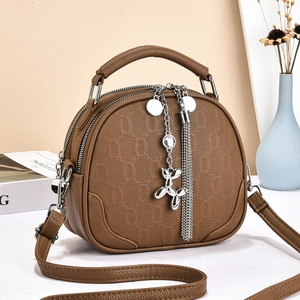 Brown shell-shaped leather crossbody bag with metal balloon dog charm and tassels