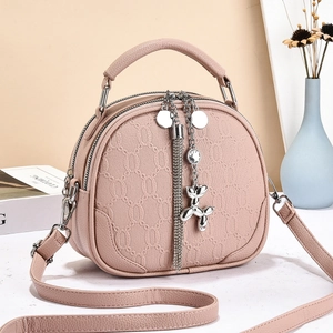 Detail of pink crossbody bag with silver chain tassel and balloon dog charm