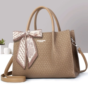 Sac fourre-tout marron tressé avec foulard décoratif et bandoulière sur surface blanche