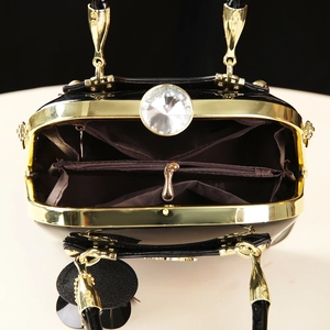 Internal view of black patent leather shell bag with gold frame and large crystal buckle
