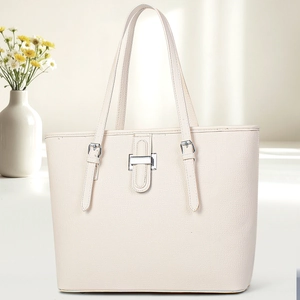 Detail of off-white lychee grain tote bag with elegant metal buckle and slim shoulder straps