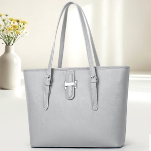 Detail of grey lychee textured leather tote bag with silver metal buckle and reinforced straps