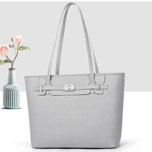 Macro detail of lychee textured leather and silver oval twist lock on a tote bag